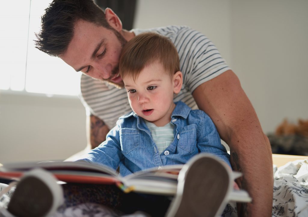 Young father reading to his toddler son. 